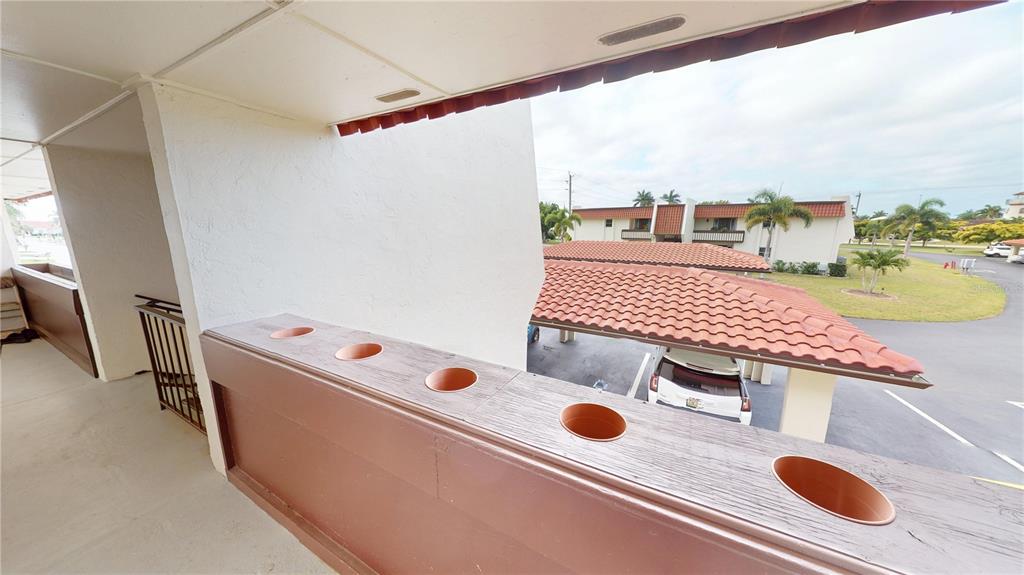 A view from a covered balcony overlooking a parking area with carports and palm trees — 311 GARVIN STREET UNIT 401C, PUNTA GORDA, FL