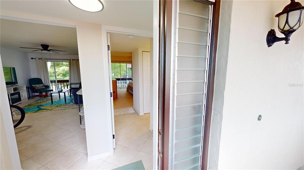 A view from a balcony looking through a doorway into a living room and bedroom — 311 GARVIN STREET UNIT 401C, PUNTA GORDA, FL
