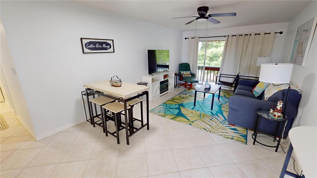 A living room and dining area feature tile flooring, a blue sofa, and a table — 311 GARVIN STREET UNIT 401C, PUNTA GORDA, FL