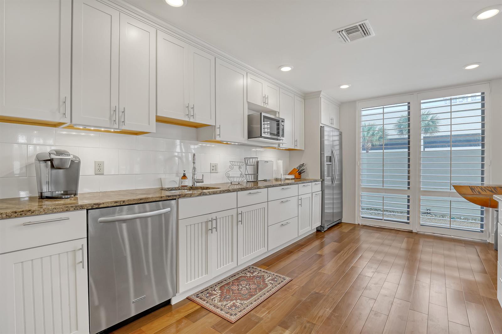 A kitchen with white cabinets, stainless steel appliances, granite countertops, and hardwood floors — 3400 N Ocean Drive # 101, Singer Island FL 33404, SINGER ISLAND, FL