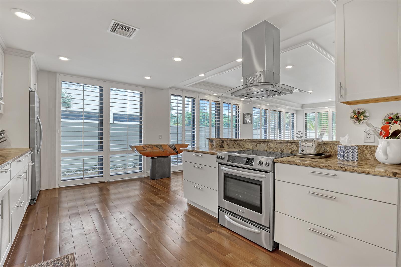 A kitchen with white cabinets, granite countertops, stainless steel appliances, and wood flooring — 3400 N Ocean Drive # 101, Singer Island FL 33404, SINGER ISLAND, FL