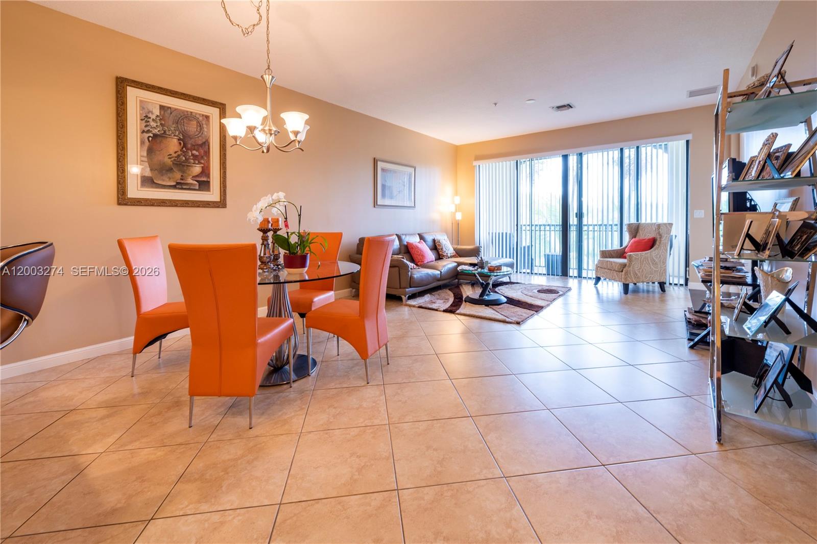 This open-concept living and dining area features tile flooring, orange chairs, and a glass table — 3020 NW 125th Ave # 317, Sunrise FL 33323, SUNRISE, FL