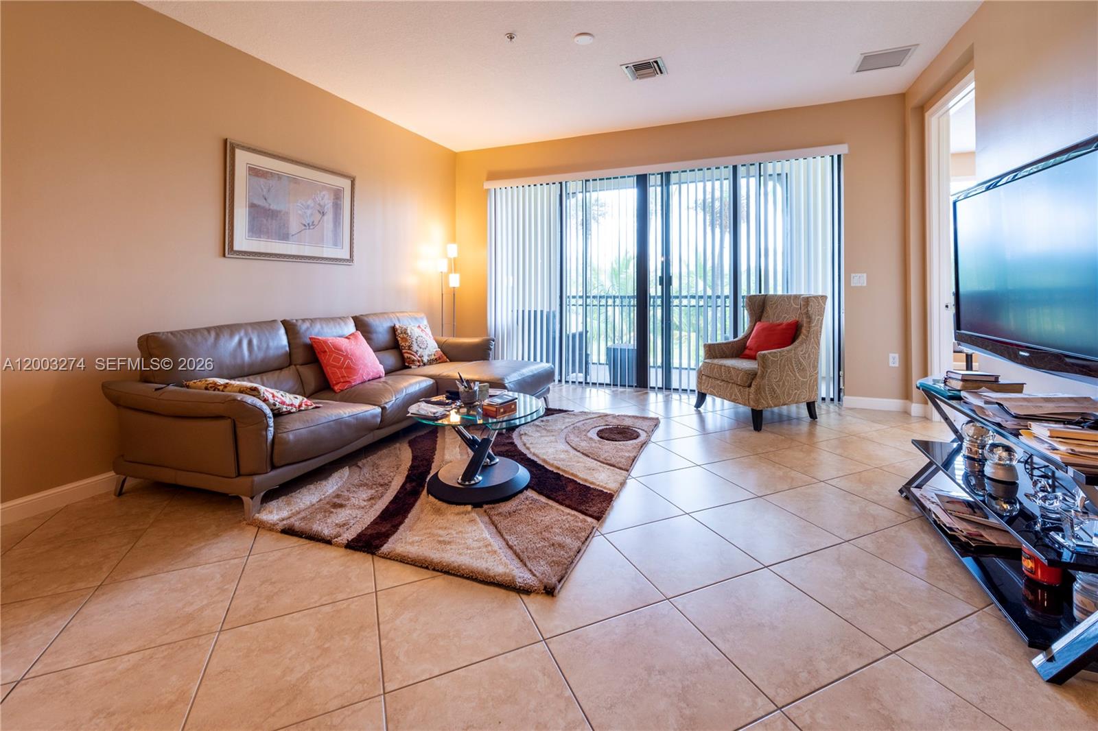 A living room features a leather sectional, patterned armchair, glass coffee table, and tile flooring — 3020 NW 125th Ave # 317, Sunrise FL 33323, SUNRISE, FL