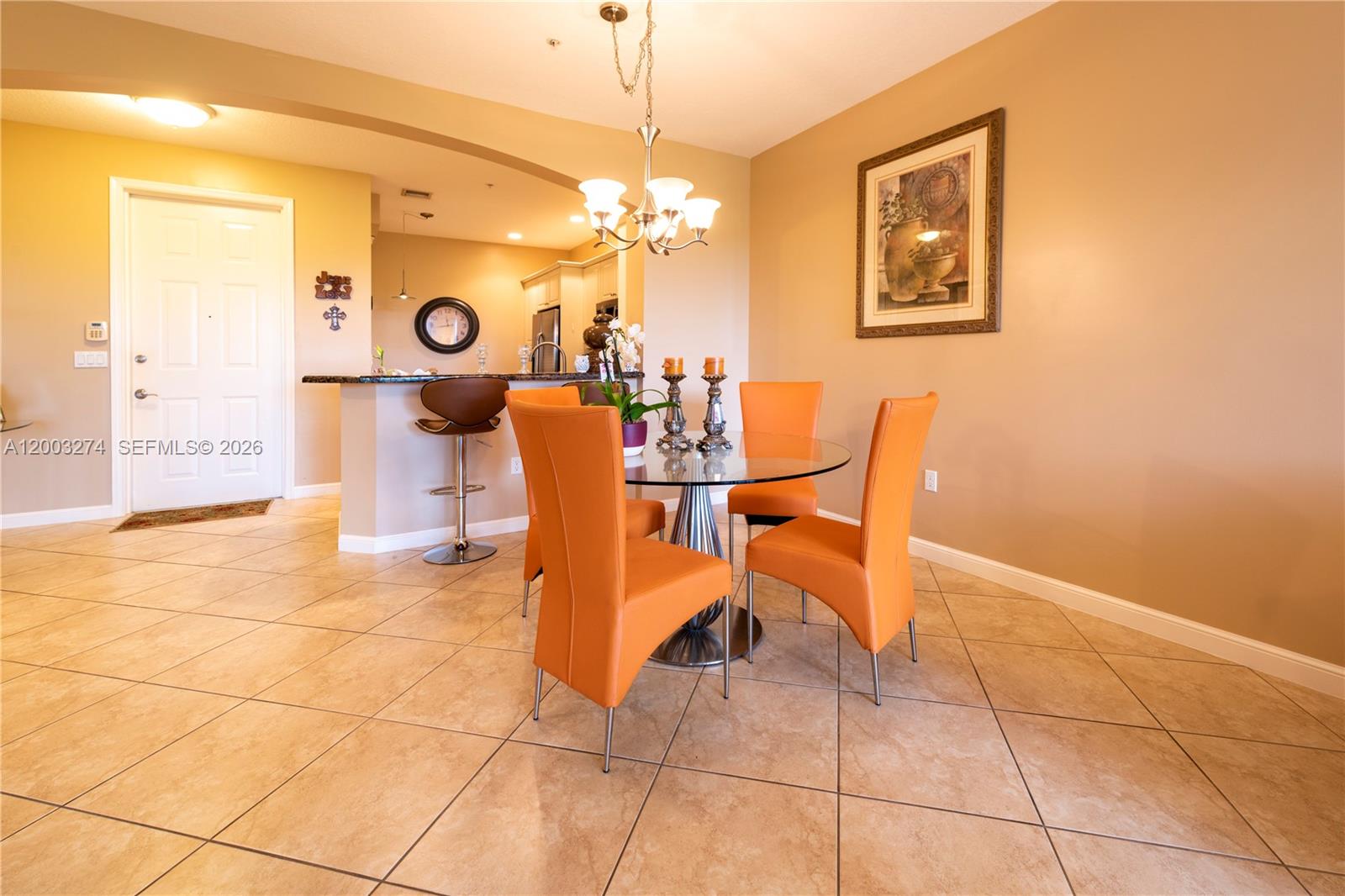 A dining area features a glass table with four orange chairs and tile flooring — 3020 NW 125th Ave # 317, Sunrise FL 33323, SUNRISE, FL