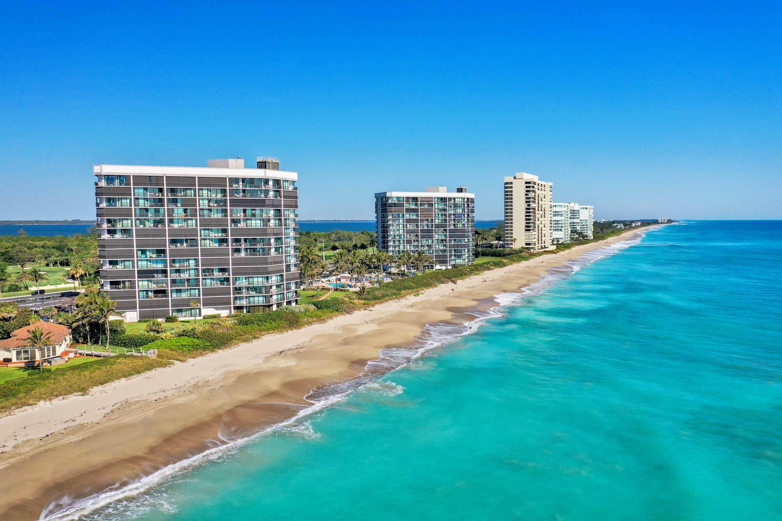 An aerial view of high-rise apartment buildings situated along a sandy beach and turquoise ocean — 8800 S Ocean Drive # 109, Jensen Beach FL 34957, JENSEN BEACH, FL