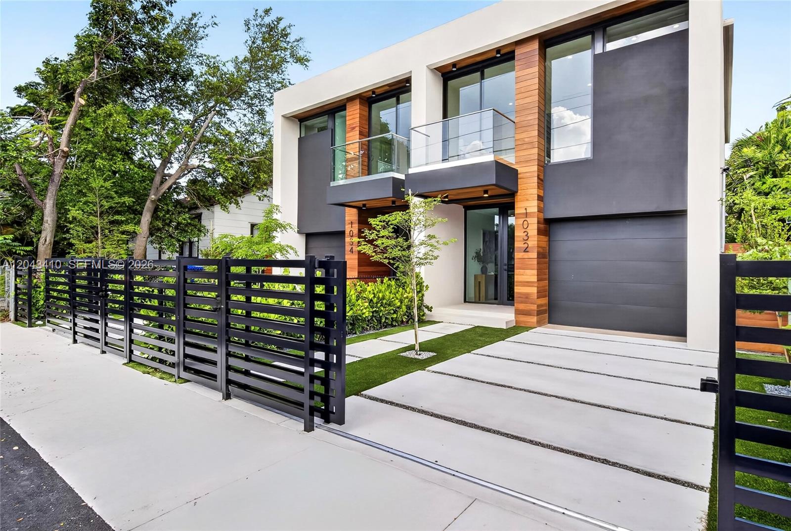 A modern two-story duplex features wood accents, glass balconies, and a black metal fence — 1032 SW 11th Ave, Miami FL 33130, MIAMI, FL