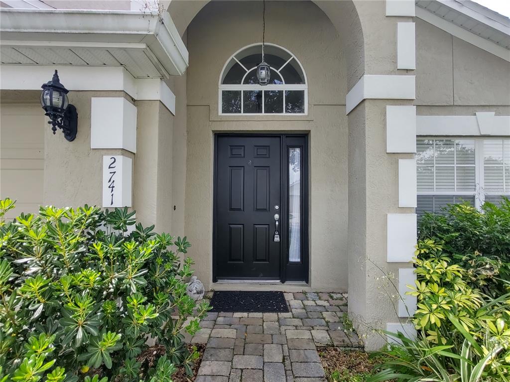 A front entryway features a black door with a sidelight and an arched transom window — 2741 BELLEWATER PLACE, OVIEDO, FL