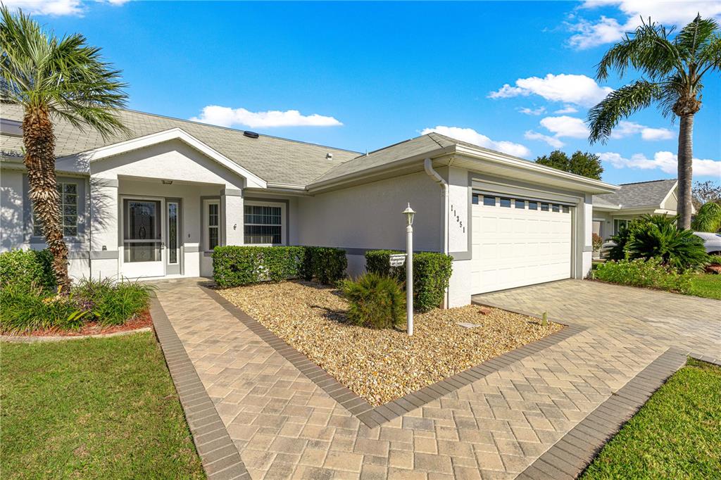 A single-story house features a paved walkway, a gravel garden, and an attached two-car garage — 11351 SE 175TH PLACE, SUMMERFIELD, FL