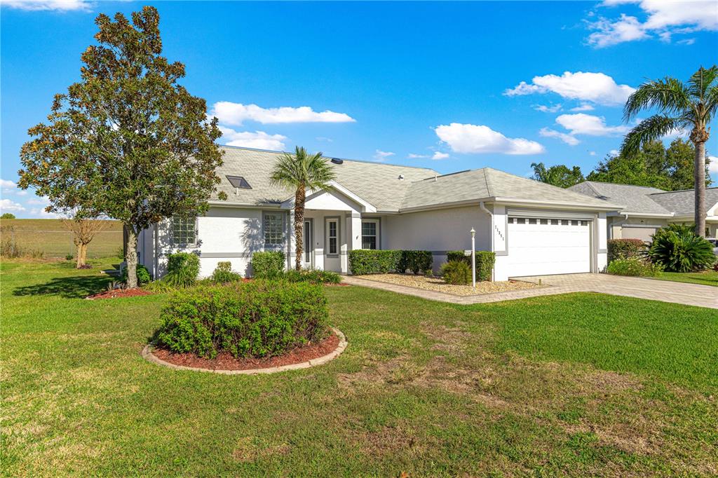 A single-story house with a white exterior, a two-car garage, and a landscaped front yard — 11351 SE 175TH PLACE, SUMMERFIELD, FL