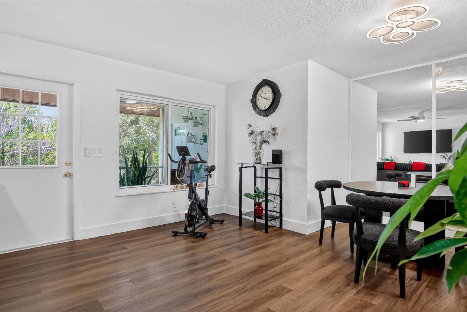 A dining area with wood-look flooring, a stationary bike, and a mirrored wall — 5930 Whispering Pine Way # 2, FL 33463, FL