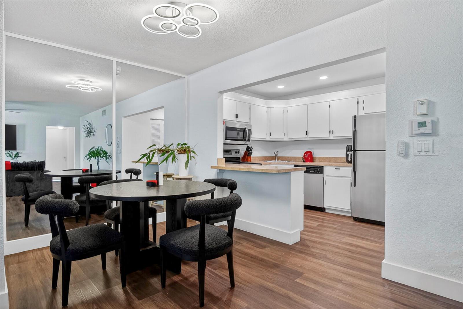 A dining area with a round table and chairs sits adjacent to a white kitchen — 5930 Whispering Pine Way # 2, FL 33463, FL