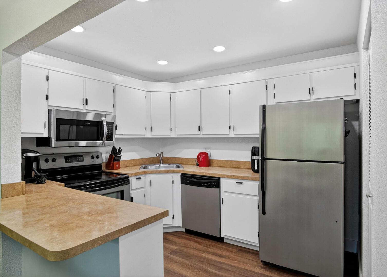 A kitchen features white cabinets, stainless steel appliances, and tan laminate countertops — 5930 Whispering Pine Way # 2, FL 33463, FL