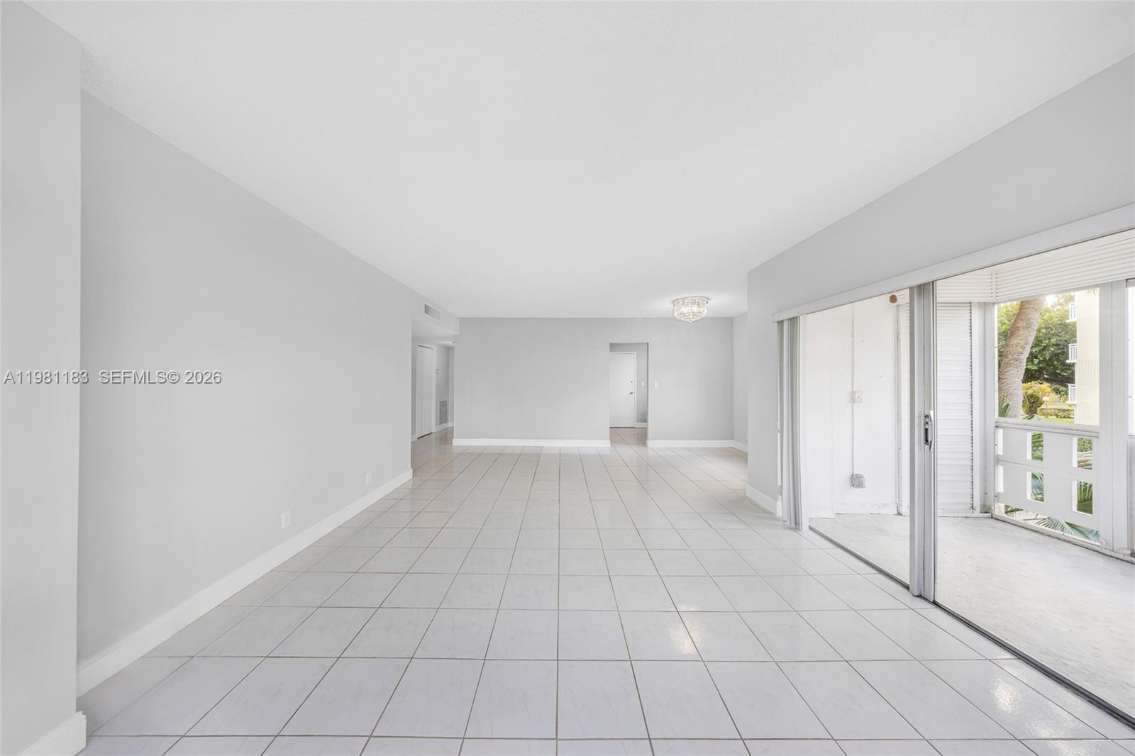 An empty living room features white tile floors, light gray walls, and a sliding glass door — 4350 Hillcrest Dr # 200, Hollywood FL 33021, HOLLYWOOD, FL