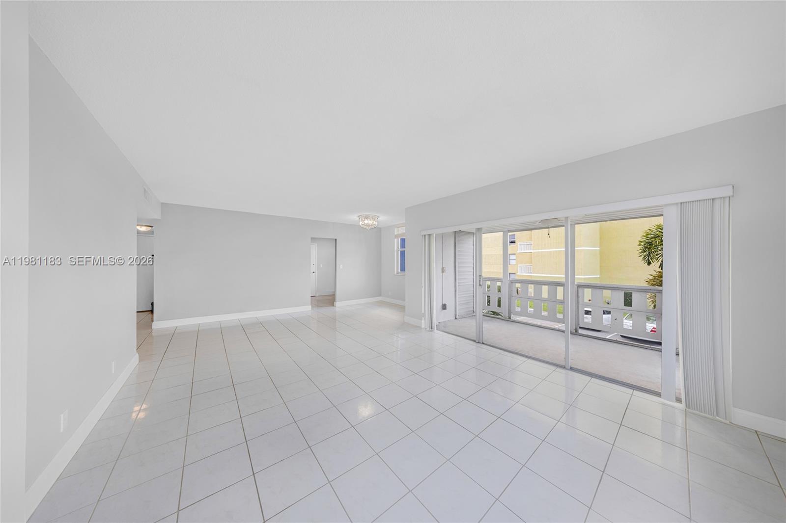 A spacious, empty living room features white tile flooring, light gray walls, and a balcony — 4350 Hillcrest Dr # 200, Hollywood FL 33021, HOLLYWOOD, FL