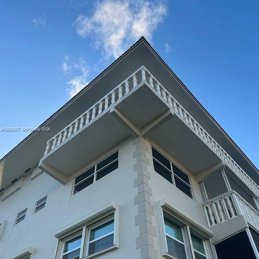 A low-angle exterior view of a white multi-story building featuring balconies with white railings — HALLANDALE BEACH, FL