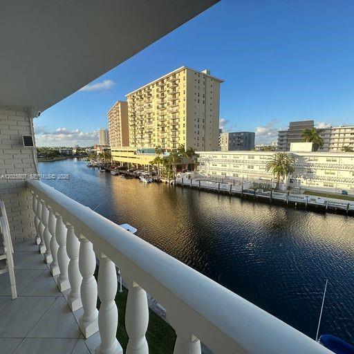 A balcony with a white balustrade overlooks a canal lined with apartment buildings and boats — HALLANDALE BEACH, FL