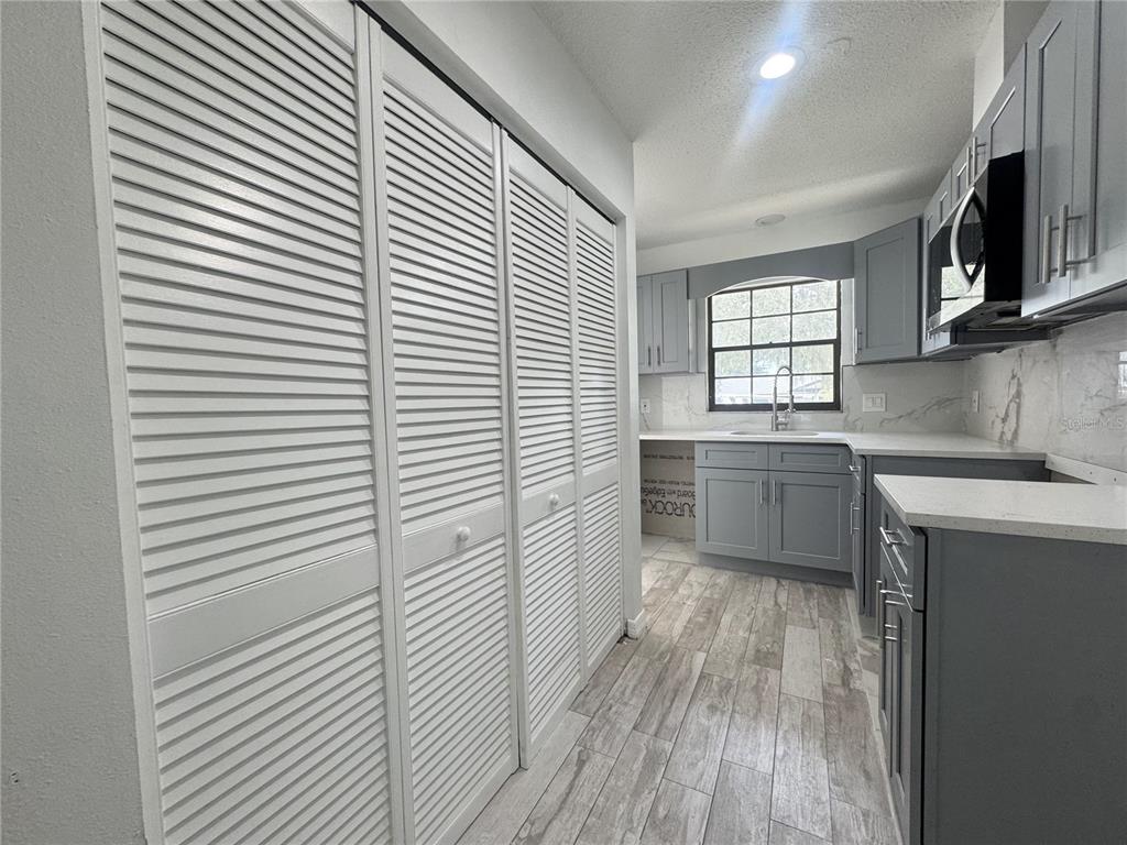 A kitchen with gray cabinets, white countertops, wood-look tile flooring, and white louvered closet doors — 2207 KARL STREET UNIT A, LEESBURG, FL