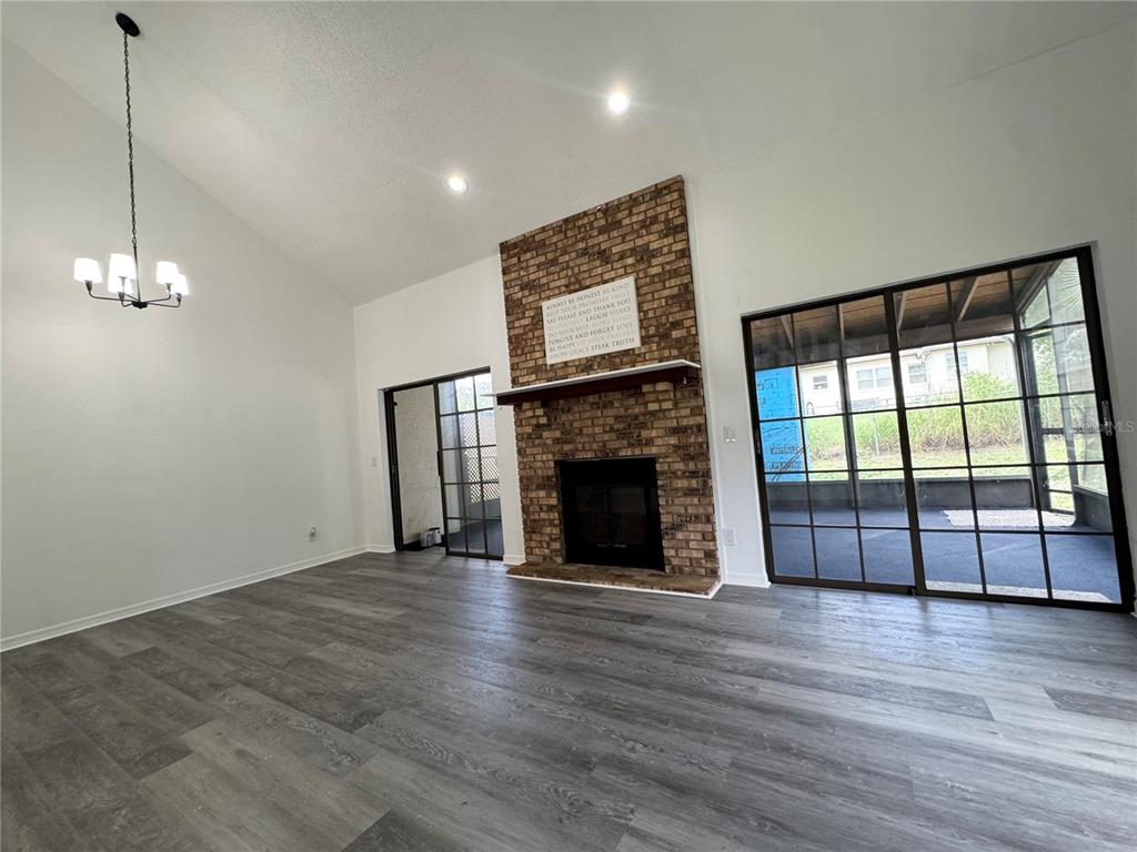 A living room features gray wood-look flooring, a brick fireplace, and sliding glass doors — 2207 KARL STREET UNIT A, LEESBURG, FL