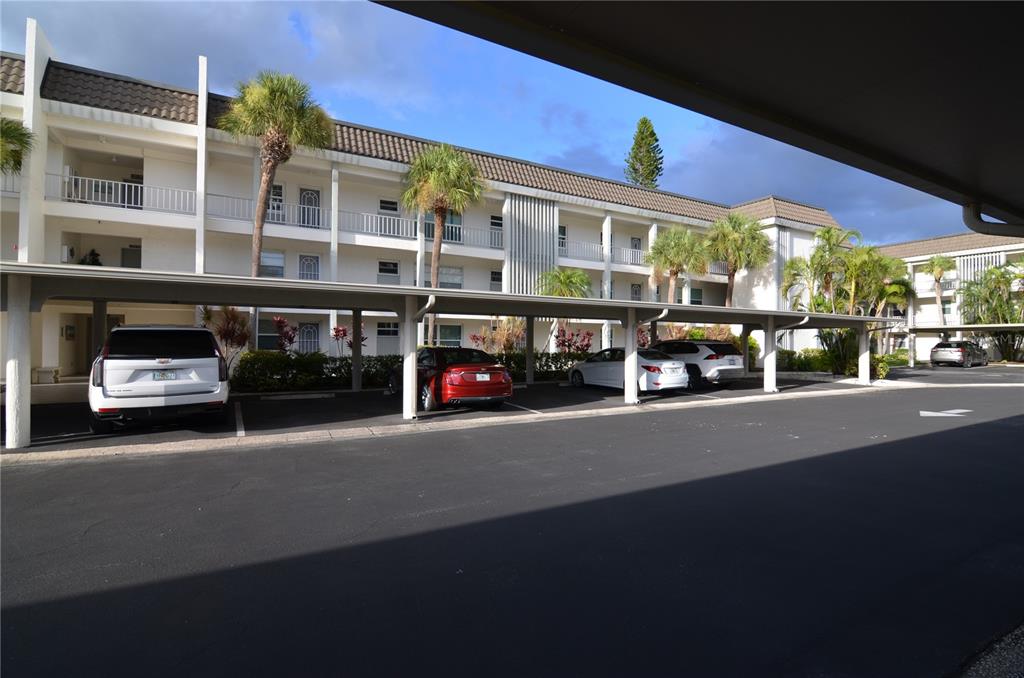 A multi-story apartment building with a covered parking area in front — 4420 EXETER DRIVE UNIT 208, LONGBOAT KEY, FL