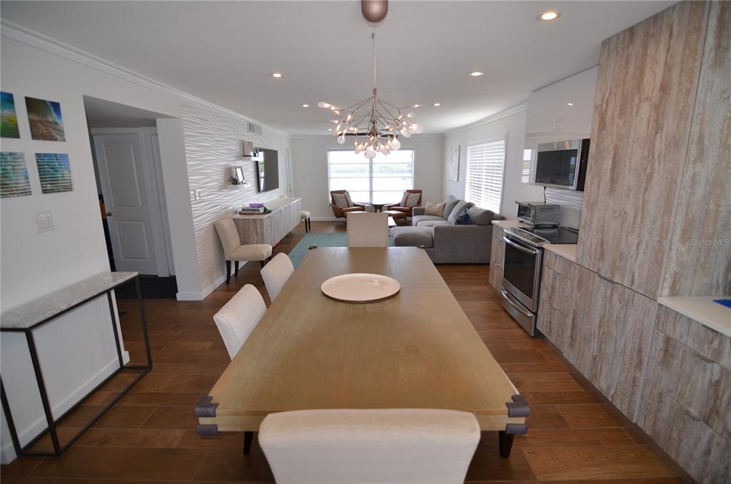 An open-concept dining and living area features wood-look tile flooring and a modern chandelier — 4420 EXETER DRIVE UNIT 208, LONGBOAT KEY, FL