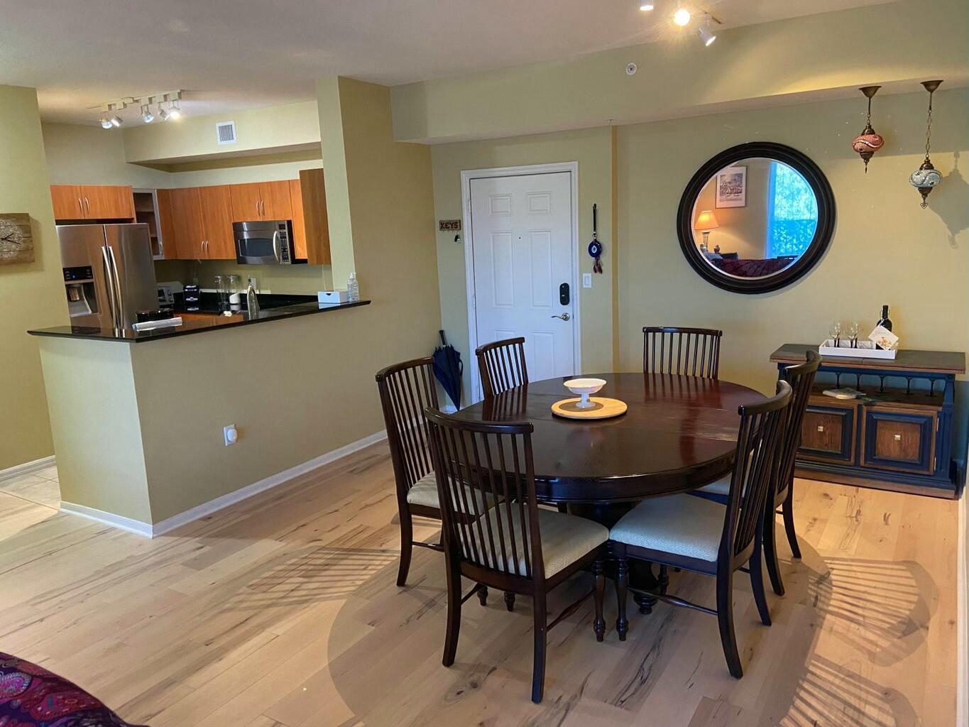 A dining area with a round wooden table, chairs, and a kitchen with stainless appliances — 802 W Windward Way # 203, Lantana FL 33462, LANTANA, FL