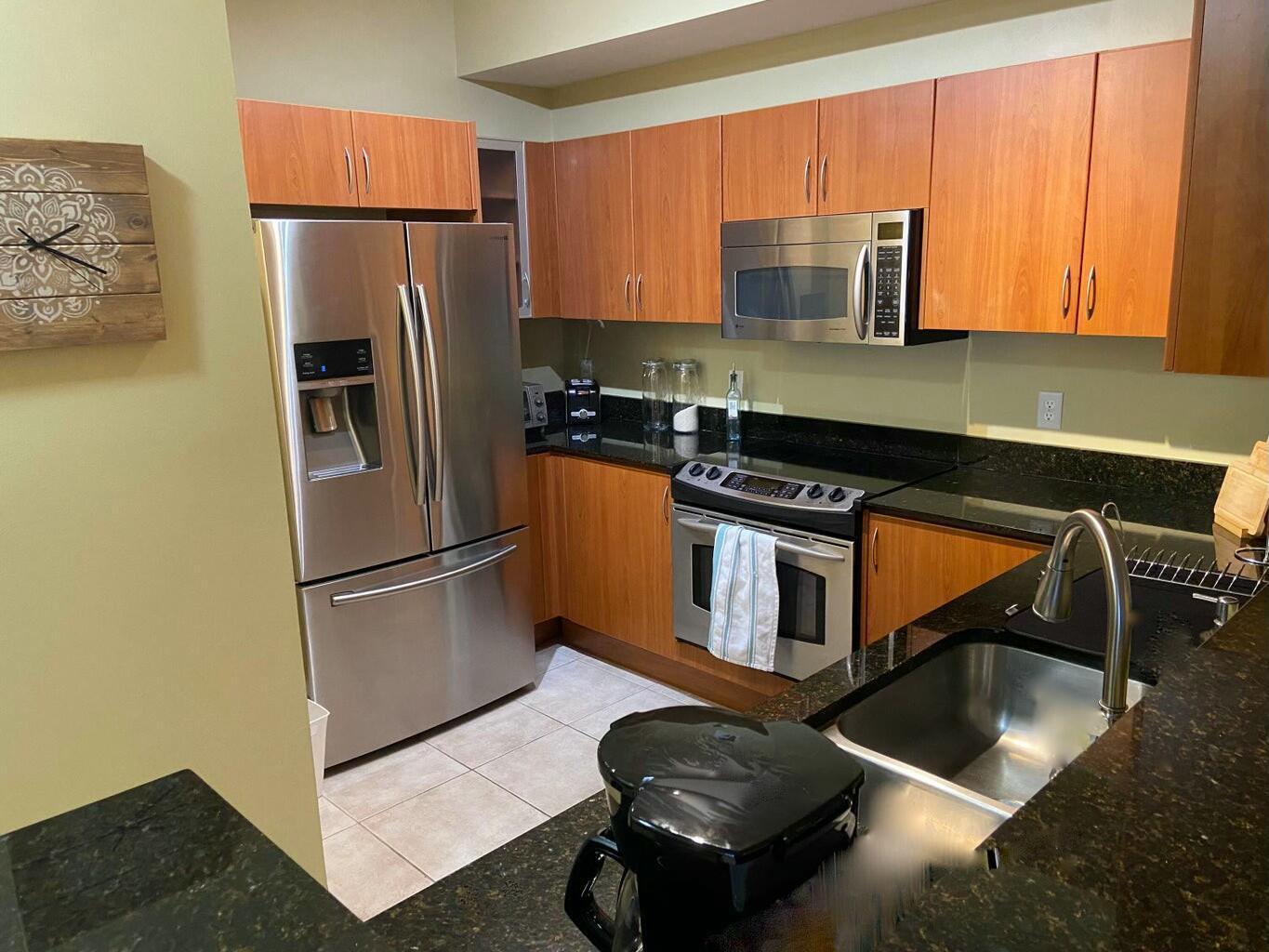 A kitchen features wood cabinets, stainless steel appliances, and dark granite countertops — 802 W Windward Way # 203, Lantana FL 33462, LANTANA, FL