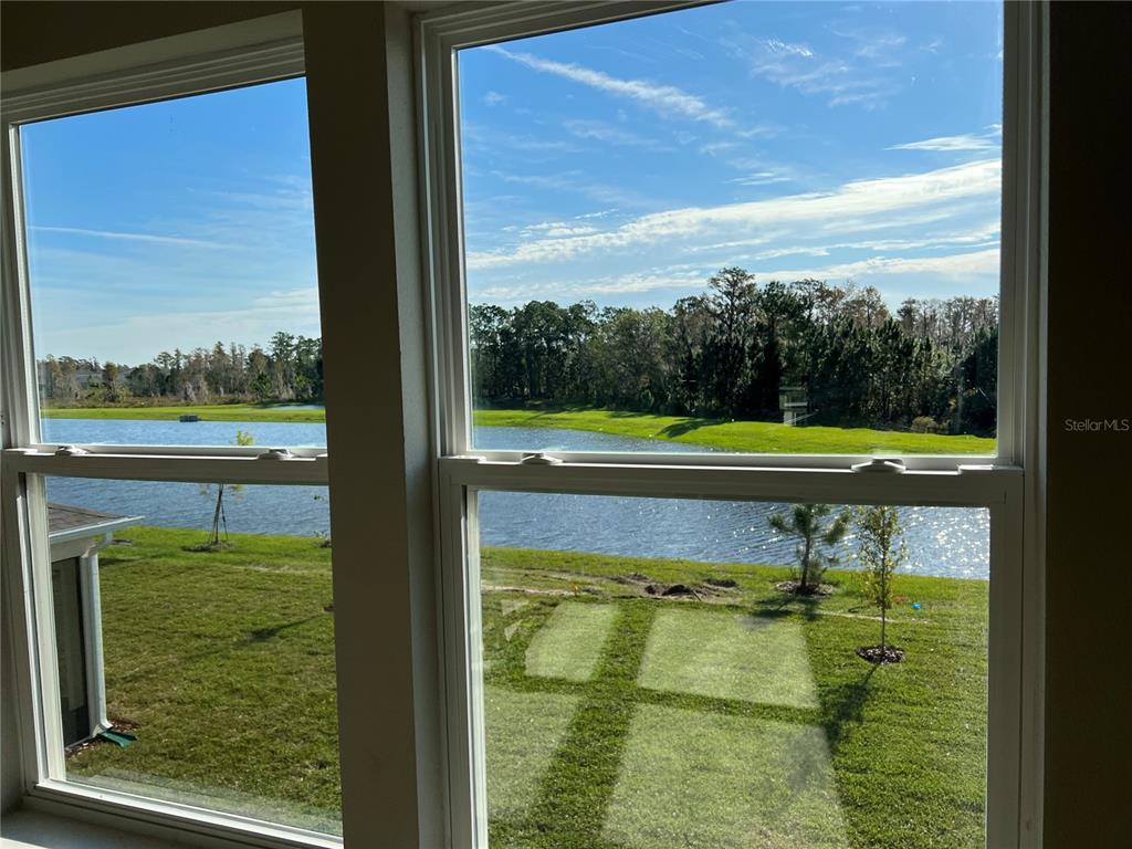 A view of a pond and grassy yard through two large windows — 17575 SAW PALMETTO AVENUE, CLERMONT, FL
