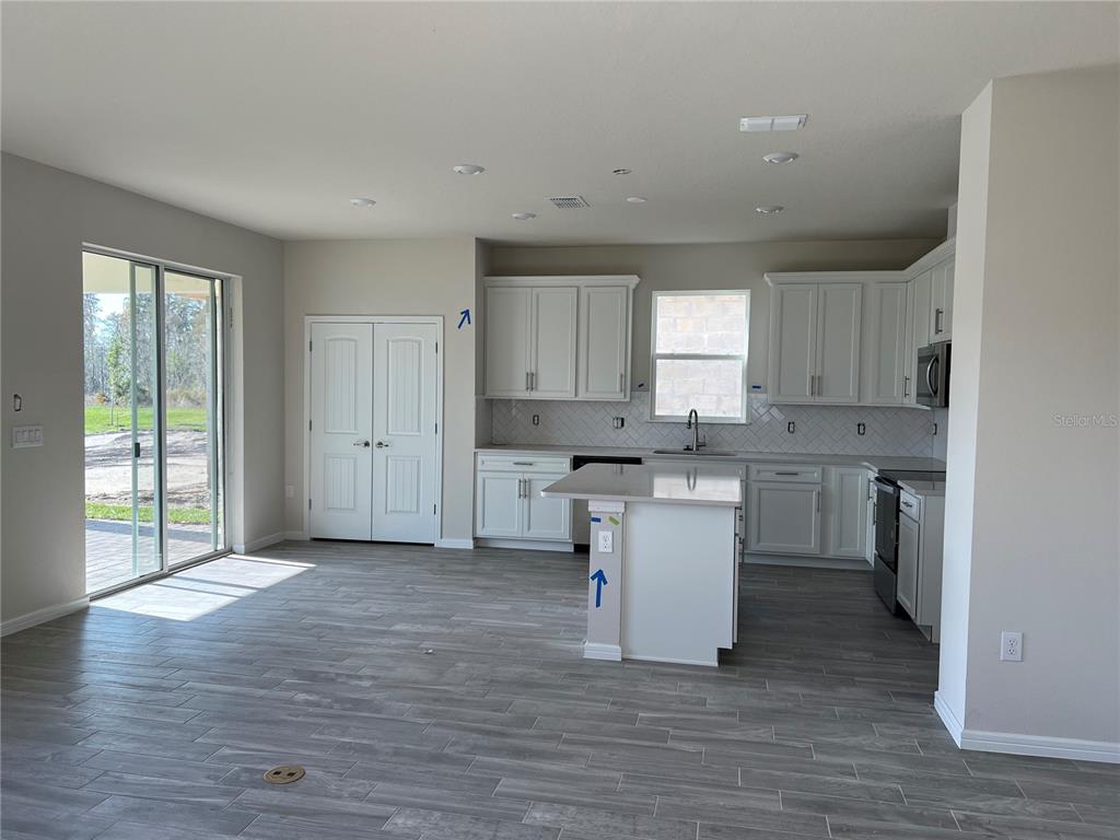 A kitchen with white cabinets, a center island, and gray wood-look tile flooring — 17575 SAW PALMETTO AVENUE, CLERMONT, FL