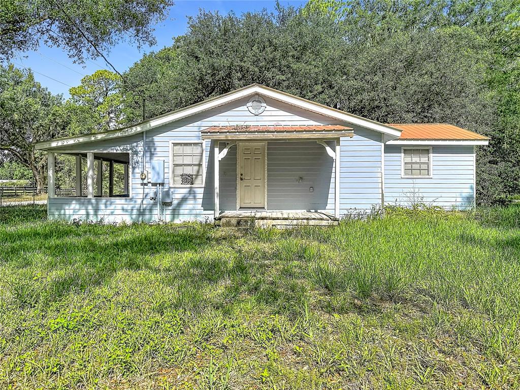 A light blue, single-story house with a metal roof and a front porch — 1007 HAWTHORN STREET, ZEPHYRHILLS, FL