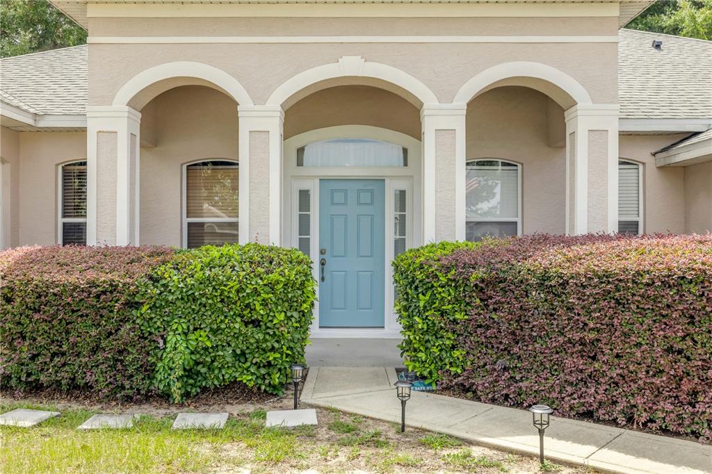 The exterior of a house features a light blue front door framed by three white arches — 36624 GRAND ISLAND OAKS CIRCLE, GRAND ISLAND, FL
