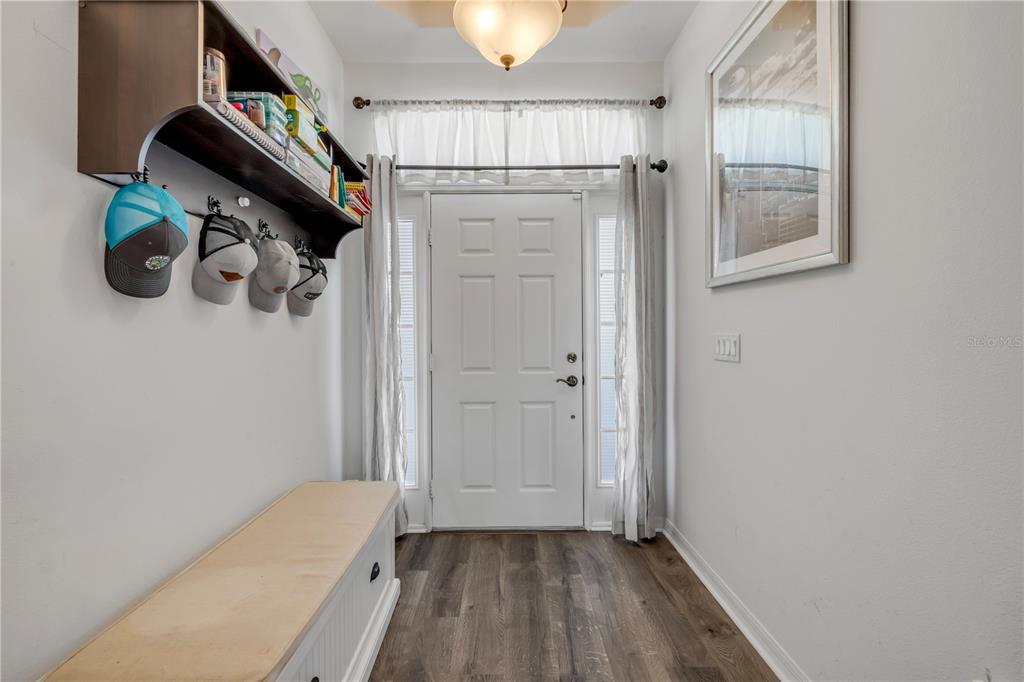 An entryway features a bench, wall-mounted coat hooks with hats, and a white front door — 36624 GRAND ISLAND OAKS CIRCLE, GRAND ISLAND, FL