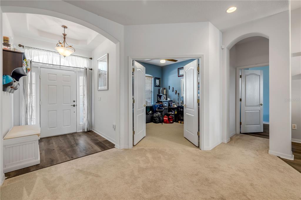 An entryway with wood-look flooring leads to a carpeted room with double doors — 36624 GRAND ISLAND OAKS CIRCLE, GRAND ISLAND, FL