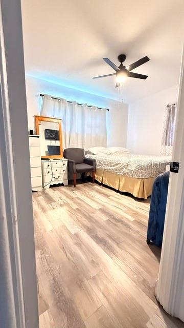 A bedroom features light wood-look flooring, a bed with a tan skirt, and a ceiling fan — 4810 DEAUVILLE DRIVE, ORLANDO, FL