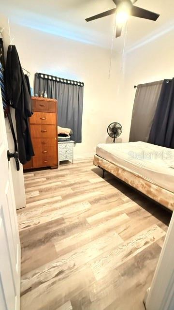 A bedroom features light wood-look flooring, a wooden dresser, a bed, and a ceiling fan — 4810 DEAUVILLE DRIVE, ORLANDO, FL