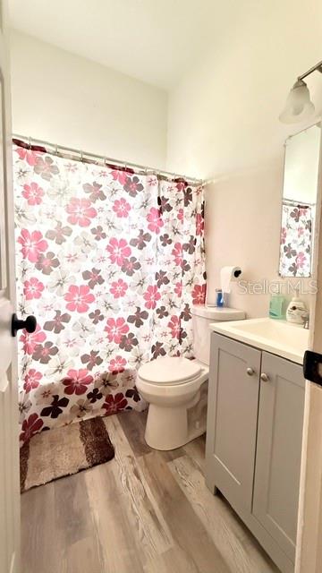 A bathroom features a floral shower curtain, a white toilet, and a grey vanity cabinet — 4810 DEAUVILLE DRIVE, ORLANDO, FL
