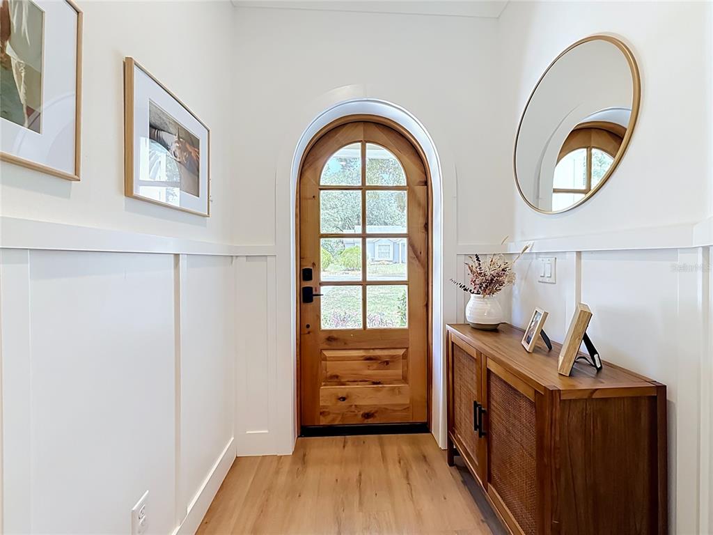 An entryway features white board-and-batten walls, a wood arched door, and a wooden console table — 2003 DONNELLY PLACE, MOUNT DORA, FL