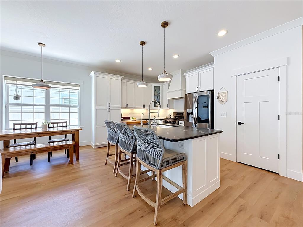 A kitchen features white cabinetry, a dark stone island with bar seating, and wood flooring — 2003 DONNELLY PLACE, MOUNT DORA, FL