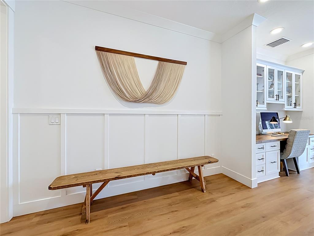 A wooden bench sits against a white wainscoted wall beneath a fiber wall hanging — 2003 DONNELLY PLACE, MOUNT DORA, FL