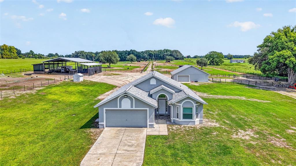 An aerial view shows a single-story house with a garage, driveway, and detached metal building — 14125 SE 175TH STREET, WEIRSDALE, FL