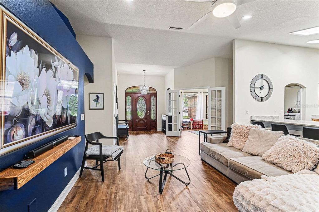 A living room features wood-look flooring, a blue accent wall, and a glass coffee table — 6040 SPRUCE POINT CIRCLE, PORT ORANGE, FL