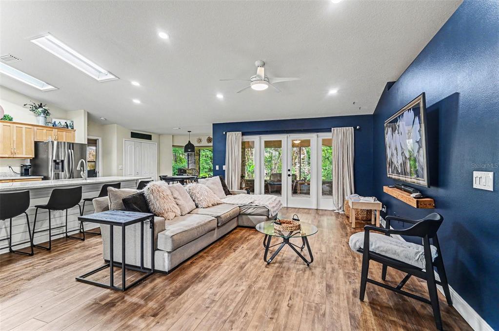 A living room with a blue accent wall, sectional sofa, and open kitchen area — 6040 SPRUCE POINT CIRCLE, PORT ORANGE, FL