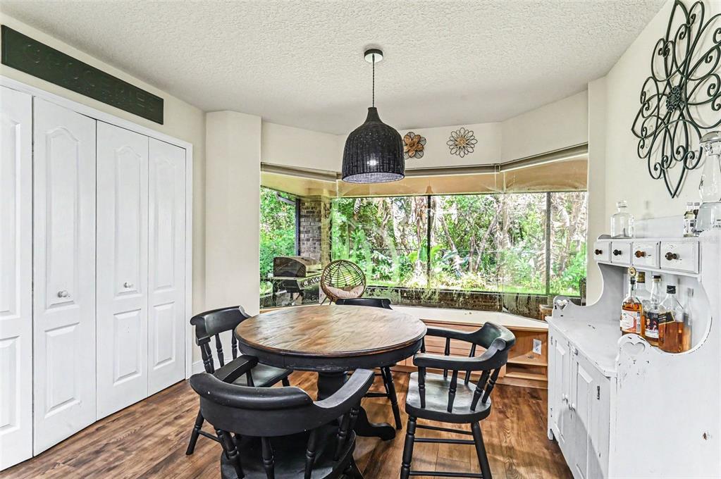 A dining room features a round wooden table, black chairs, and a large bay window — 6040 SPRUCE POINT CIRCLE, PORT ORANGE, FL