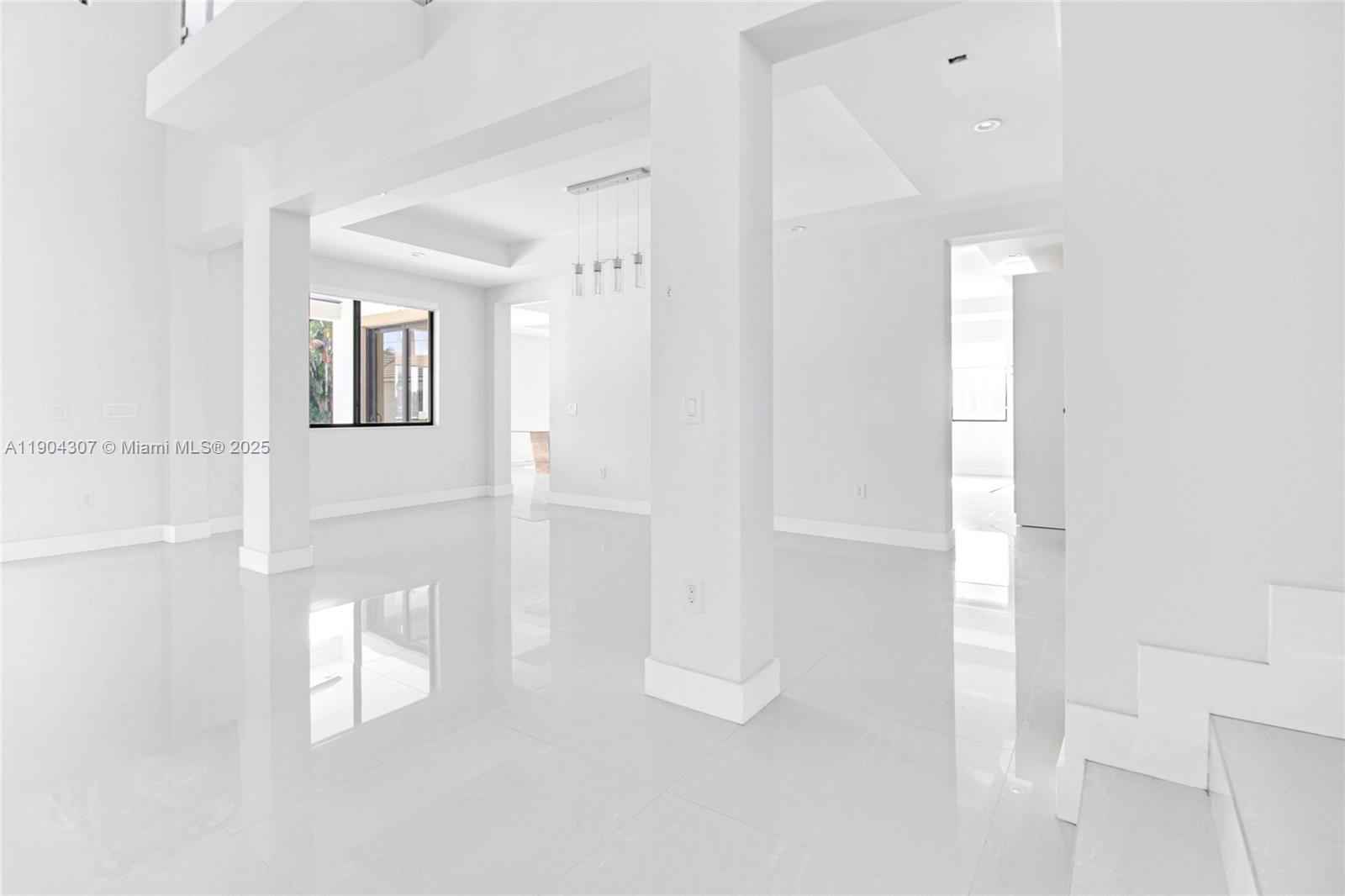 A bright, minimalist living space features white tile floors, high ceilings, and structural columns — 12890 NW 2nd St, Miami FL 33182, MIAMI, FL