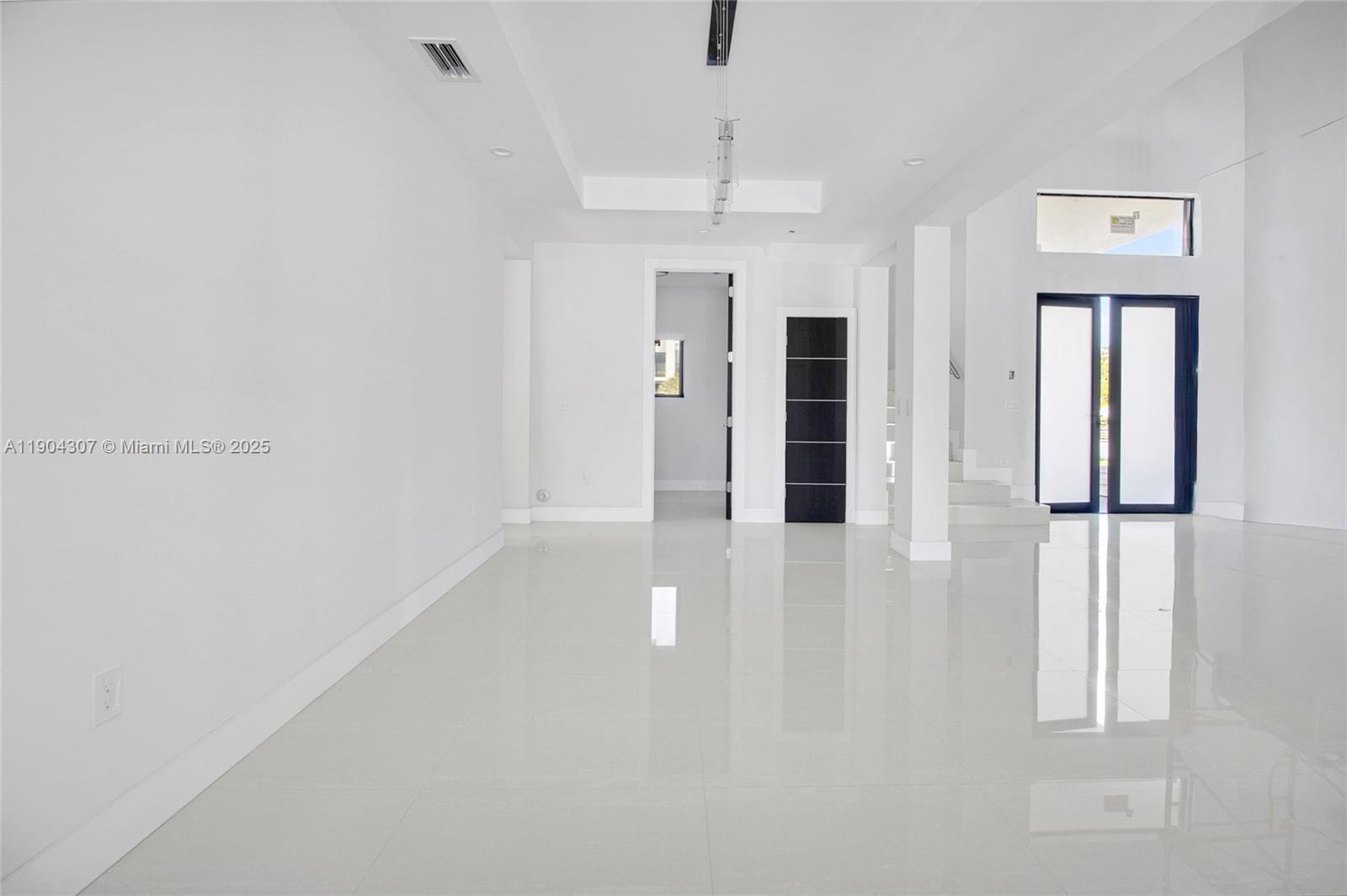 A bright, minimalist room features white walls, glossy tile floors, and a dark door — 12890 NW 2nd St, Miami FL 33182, MIAMI, FL