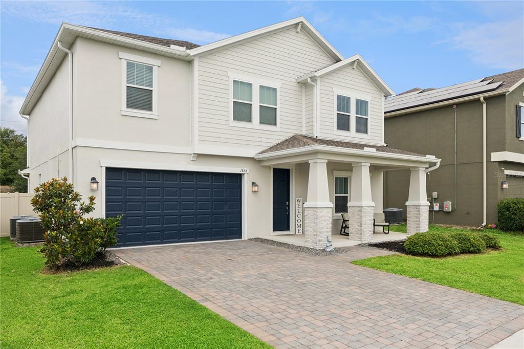 A two-story house with a dark blue garage door, stone-accented porch, and paved driveway — 1855 BLACK MAPLE PLACE, OCOEE, FL