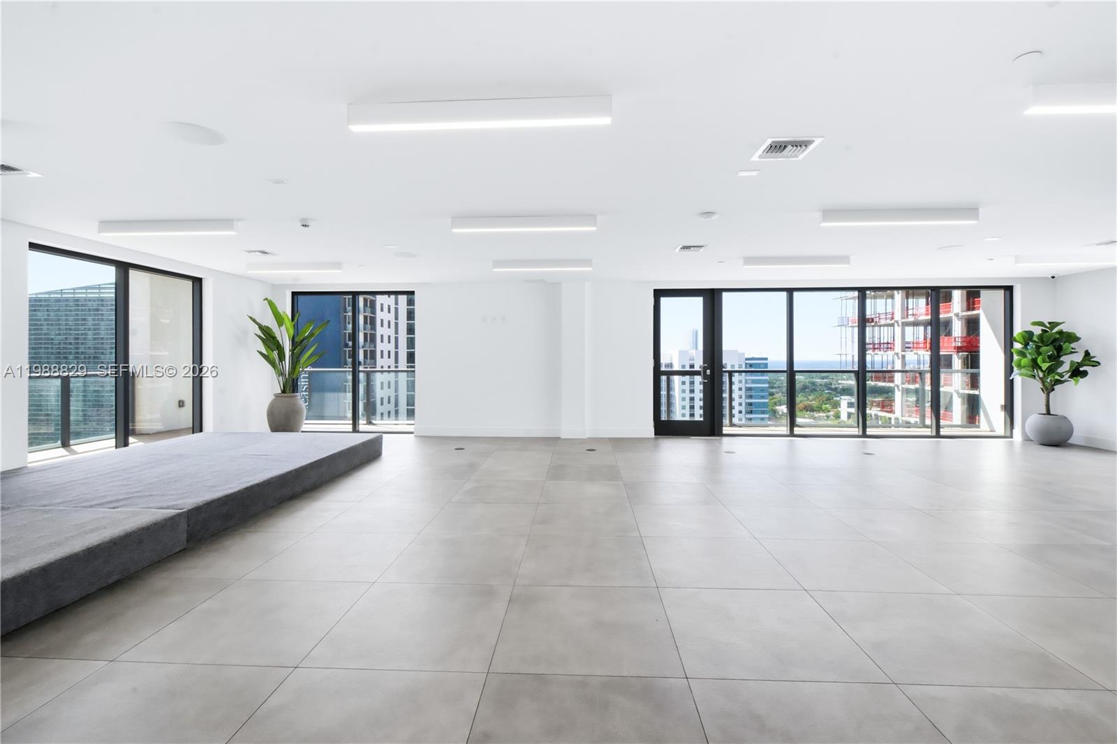 A bright, minimalist room features large floor tiles, a raised platform, and floor-to-ceiling windows — 239 SW 9th St # 2401, Miami FL 33130, MIAMI, FL