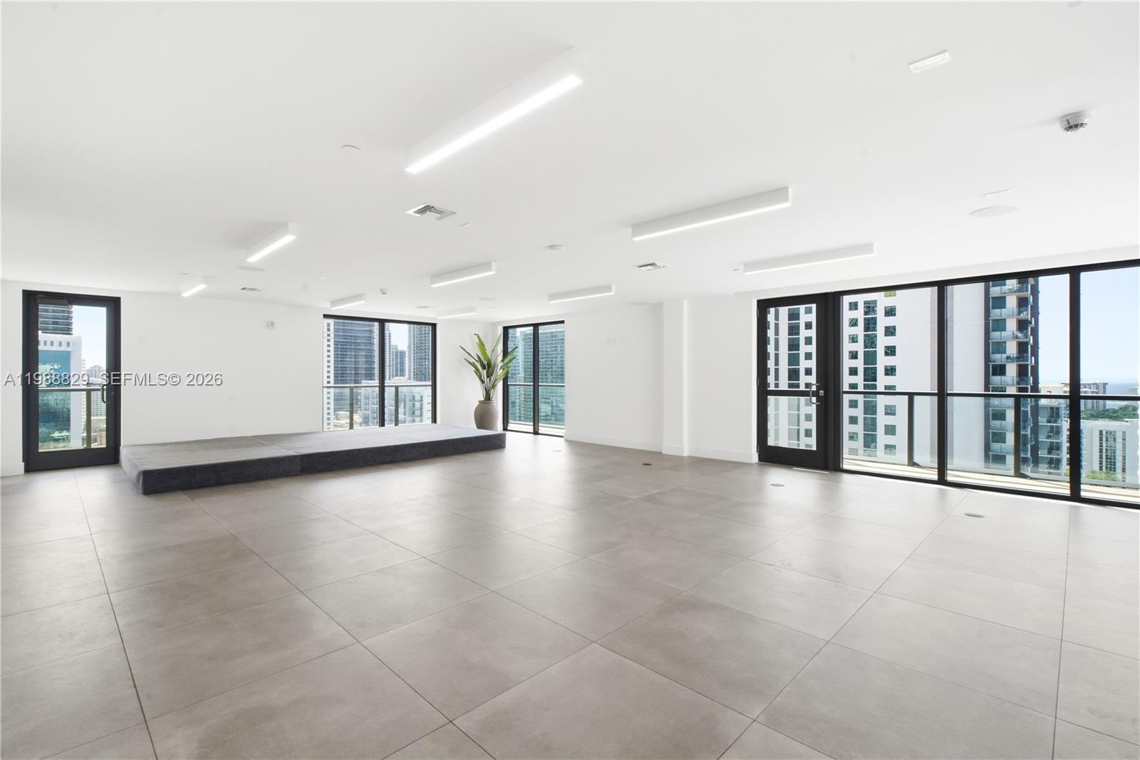 A bright, empty room features large floor tiles, a raised platform, and floor-to-ceiling windows — 239 SW 9th St # 2401, Miami FL 33130, MIAMI, FL