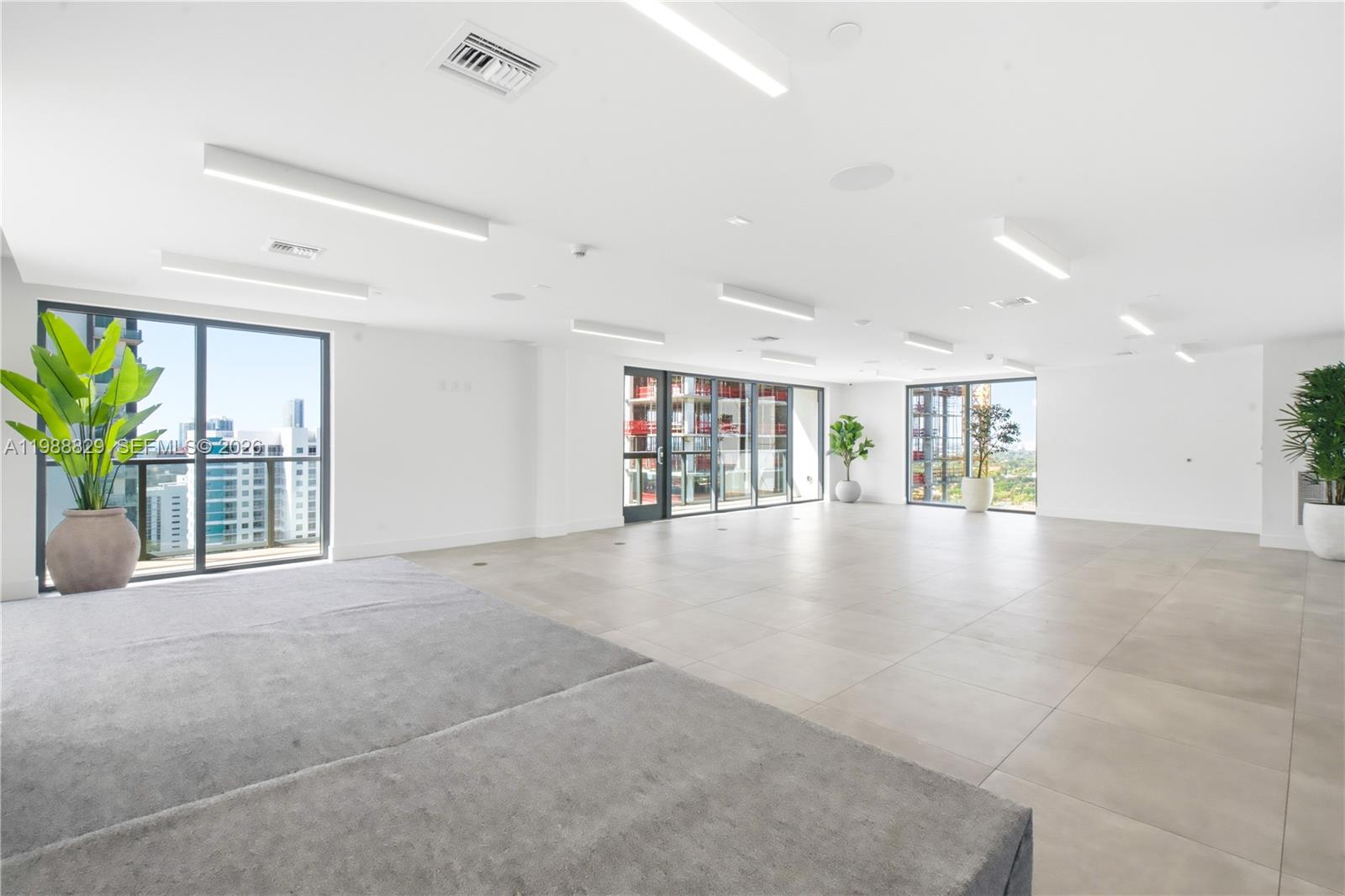 A bright, open-plan room features large windows, light tile flooring, and several potted plants — 239 SW 9th St # 2401, Miami FL 33130, MIAMI, FL