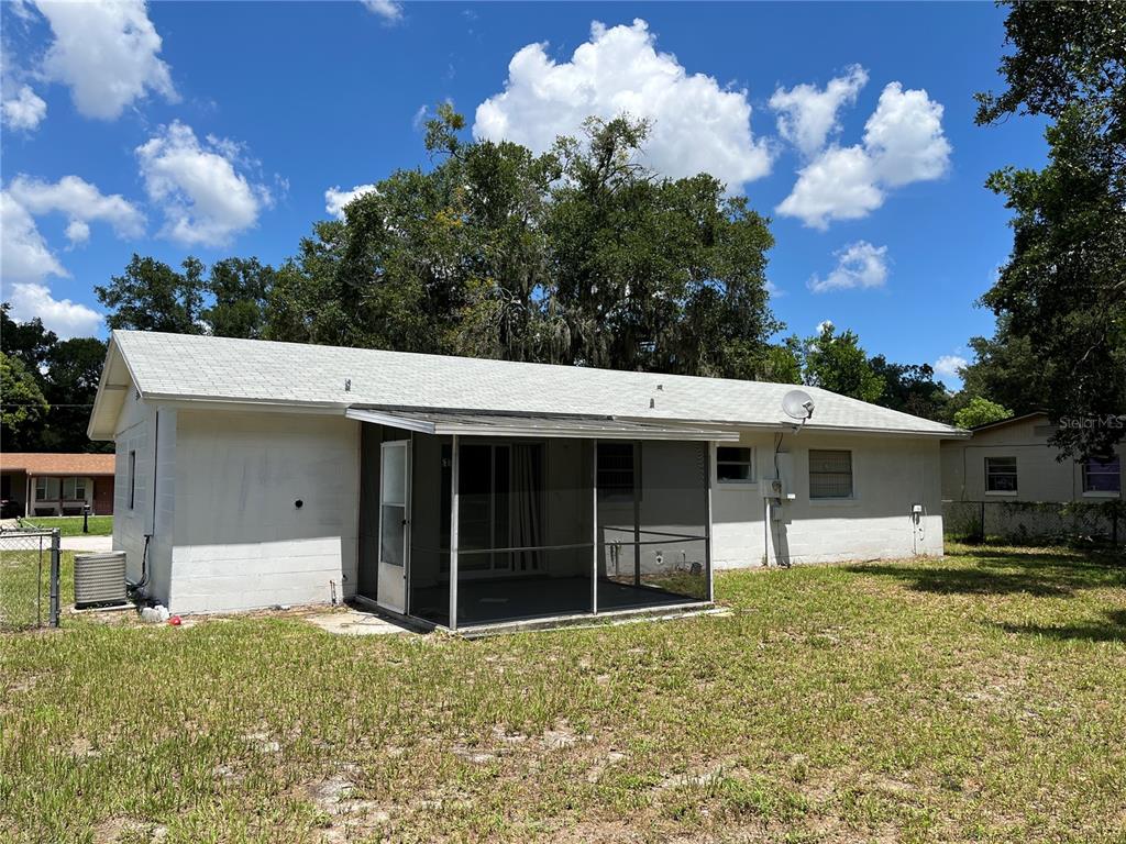 The back exterior of a single-story house features a screened-in porch and a grassy yard — 605 PLUM LANE, ALTAMONTE SPRINGS, FL