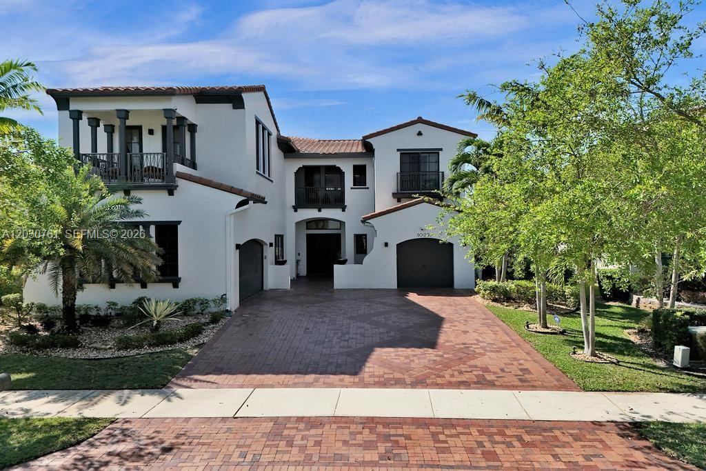 A two-story stucco house features a brick driveway, multiple balconies, and a two-car garage — 10292 Emerson St, Parkland FL 33076, PARKLAND, FL